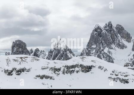 La neige couvre les sommets des montagnes dans les Dolomites, en Italie. Ce paysage hivernal montre les Trois Pics et les zones alpines sous un ciel nuageux. Banque D'Images