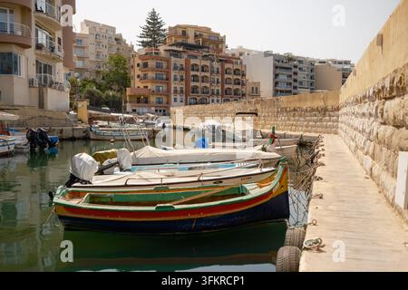 Bateaux de pêche traditionnels maltais en bois colorés amarrés dans un petit port près de St Pauls Beach Bugibba, Malte Banque D'Images