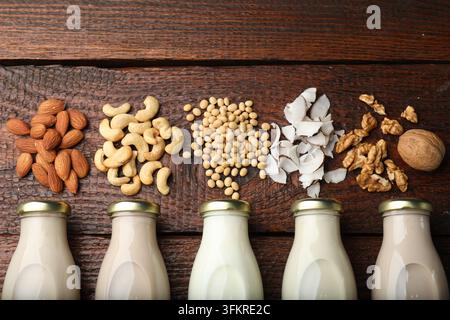 Bouteilles contenant différents types de lait végétal et ingrédients sur une table en bois, mise à plat Banque D'Images