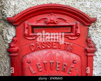 Boîte aux lettres traditionnelle italienne vintage en fonte rouge montée sur un mur texturé à Belprato, Brescia, Italie. Concept pour le service postal, la livraison du courrier, I Banque D'Images