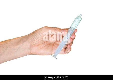 Vue latérale d'une main tenant une seringue orale en plastique transparent remplie d'un liquide médical blanc, isolée sur un fond blanc Banque D'Images