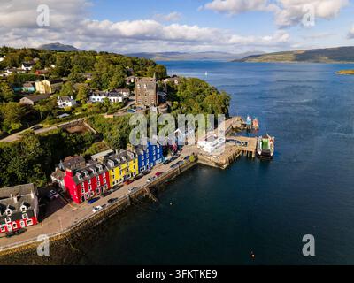 Bâtiments colorés du front de mer à Tobermory, Île de Mull, Écosse, avec le ferry amarré au quai par une journée ensoleillée, vue aérienne en hauteur Banque D'Images