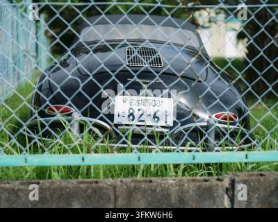 Porsche 356 noir classique garé sur l'herbe côtière avec des palmiers à Aichi, Japon Banque D'Images