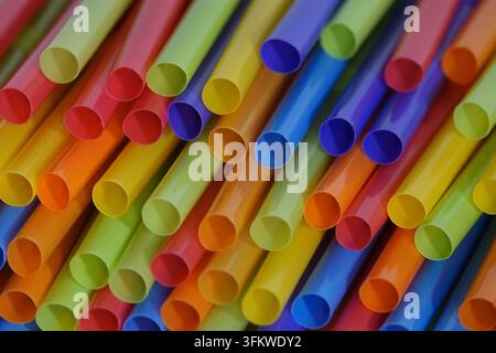 Un gros paquet de pailles en plastique colorées est présenté empilé dans une vue diagonale en gros plan. Banque D'Images