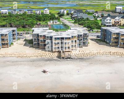 Vue aérienne de condominiums en bord de plage avec balcons en bois, sacs de sable le long des dunes et une petite tente sur la plage de sable à North Topsail Beach, No Banque D'Images