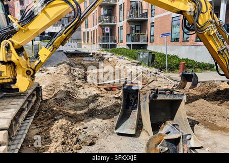 Travaux routiers et développement des infrastructures urbaines, pelleteuse jaune déblayant le sable et creusant une tranchée sur le chantier à Viborg, Danemark Banque D'Images