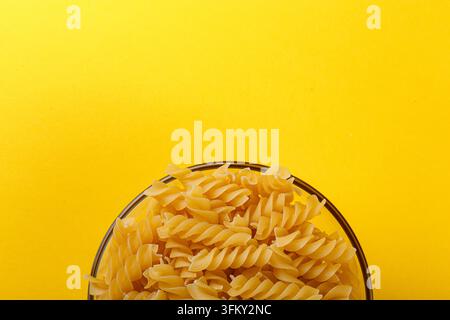 Différents types et formes de pâtes italiennes sèches sur un fond jaune en gros plan Banque D'Images