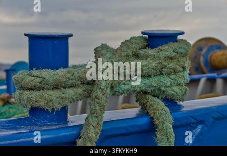 Close-up d'une corde d'amarrage verte enroulée autour de bollards peints en bleu à bord d'un navire dans le port de Rafina, Attique orientale, Grèce Banque D'Images