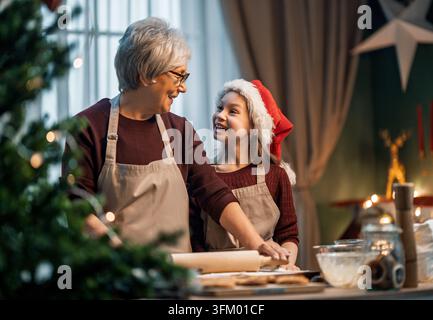 Scène réconfortante d'une grand-mère et de sa petite-fille qui partagent un moment de baking pour les fêtes. La joie de préparer des biscuits ensemble apporte chaleur et bonheur Banque D'Images