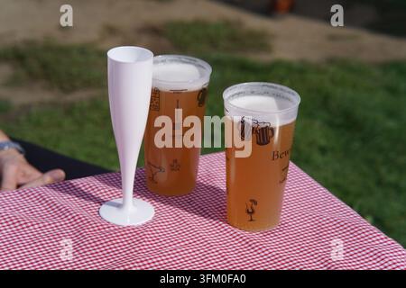 Deux pintes de bière et une flûte vide sur une table à carreaux au Food Festival de Royal Tunbridge Wells, en Angleterre. Banque D'Images