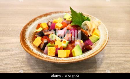 Bol de sushi chirashi japonais coloré avec saumon, thon, anguille, avocat, tamago, œufs de saumon et sashimi frais assortis servis sur du riz à sushi. Banque D'Images