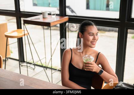 Une photo horizontale authentique, intacte, à grand angle d'une jeune femme thaïlandaise heureuse de la région d'Isan dans la vingtaine, souriant joyeusement tout en regardant Banque D'Images