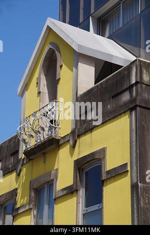 Façade jaune d'un bâtiment résidentiel arborant une rambarde de balcon ornée et des détails architecturaux patinés Banque D'Images