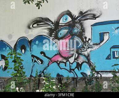Personnage et lettres de graffitis aux couleurs vives en peinture en aérosol ornant un mur urbain Banque D'Images
