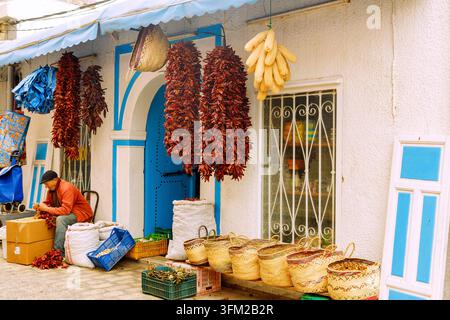 Piment de Baklouti séché (poivre Baklouti, piment fort) utilisé pour faire de la harissa, et paniers en osier dans une boutique du souk de la médina de Nabeul, Tunisie Banque D'Images