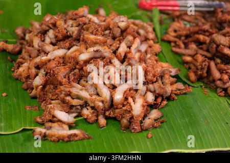 Un plan rapproché en hauteur capture un porc écarlate thaïlandais fraîchement cuit et coupé (Moo Tod) disposé sur une feuille de banier verte dans un traditionnel Banque D'Images