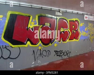 Lettres graffiti rouges et jaunes WAR peintes sur un mur de béton gris dans un passage souterrain Banque D'Images