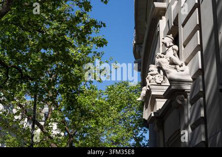 Des sculptures en pierre ornées ornent la façade d'un bâtiment historique sur Aldwych, à Westminster, Londres, mettant en valeur un art architectural classique. Banque D'Images