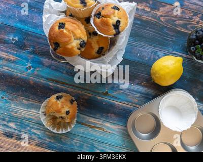 Muffins aux myrtilles fraîchement cuits avec des ingrédients de boulangerie sur un fond en bois rustique Banque D'Images