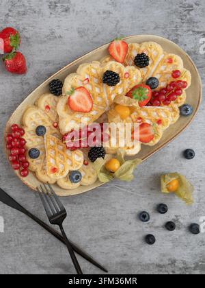 Petit-déjeuner composé de crêpes gaufrées garnies de baies fraîches et de fruits de saison Banque D'Images
