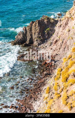 Côte accidentée à Lesbos, Grèce, avec des eaux turquoise de la mer Égée qui se brisent contre des roches volcaniques et des falaises abruptes couvertes de végétation méditerranéenne. Banque D'Images