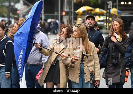 USA. 26 sep., 2026. Une femme lutte pour fermer son parapluie alors qu'elle et une amie sont prises dans une forte rafale de vent d'un nor'easter en marchant sur la Fifth Avenue à New York, New York, le 26 septembre 2026. Des rafales de vent atteignant jusqu'à 50 mph et des inondations côtières sont attendues ce week-end alors qu'un nor'easter frappe la côte Est. (Photo par Anthony Behar/Sipa USA) Crédit : Sipa USA/Alamy Live News Banque D'Images