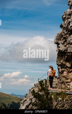 Un randonneur se tient sur une corniche rocheuse à Saxer Lucke, Appenzell, Suisse, profitant de vues à couper le souffle sur les montagnes et les vallées environnantes. Un paysage parfait pour les amateurs d'aventure et les amoureux de la nature. Banque D'Images
