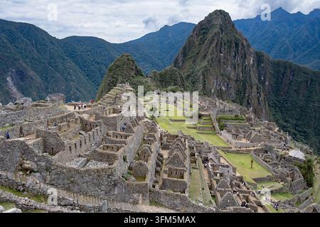 Vue élevée des terrasses en pierre, des champs agricoles et des murs de pierre de la citadelle inca de Machu Picchu au Pérou avec la montagne Huayna Picchu en arrière-plan. Banque D'Images