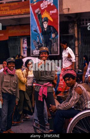 Personnes dans la rue avec une affiche patriotique derrière elles, Phnom Penh, septembre 1988. g Banque D'Images