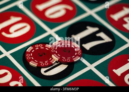 Une table de roulette verte de casino présente des jetons rouges placés sur le numéro vingt. Des jetons empilés recouvrent le zéro noir pendant la partie en cours. Banque D'Images