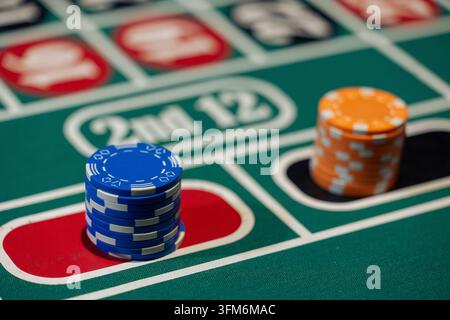 Disposition verte d'une table de roulette avec des mises placées sur les champs rouge et noir utilisant des piles de jetons bleus et orange. Banque D'Images