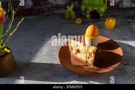 Tranche de pain traditionnel Paska Pasca de Pâques sur une assiette avec des décorations de Pâques et une lumière dramatique créant une nature morte alimentaire festive et atmosphérique Banque D'Images
