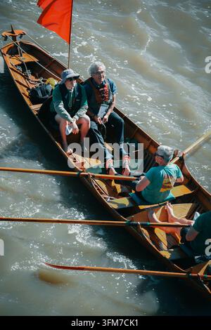 Petit équipage d'aviron en chemises vertes se détendant dans un bateau en bois pendant la Great River Race le 12 septembre 2026, Londres Banque D'Images