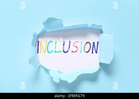 Concept d'inclusion et de diversité, texte coloré écrit sur du papier blanc révélé à travers un fond bleu clair déchiré pour la culture d'entreprise et l'égalité Banque D'Images