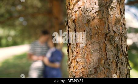Un jeune couple heureux vêtu dans le style des années 1920 profite d'un moment romantique en plein air. Ils s'embrassent, discutent et sourient ensemble sous un grand arbre dans un Banque D'Images