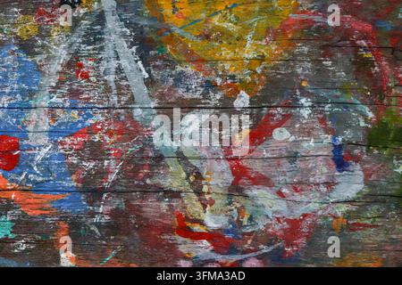 Taches de peinture bleue, rouge, orange et jaune sur une surface de table en bois vieilli, texture épaisse stratifiée, fond abstrait Banque D'Images