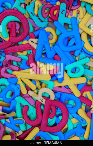 Lettres de l'alphabet en plastique usagées en bleu, bleu-vert, jaune, rouge et rose empilées dans une boutique d'articles d'occasion au marché du week-end de Chatuchak, Bangkok Banque D'Images