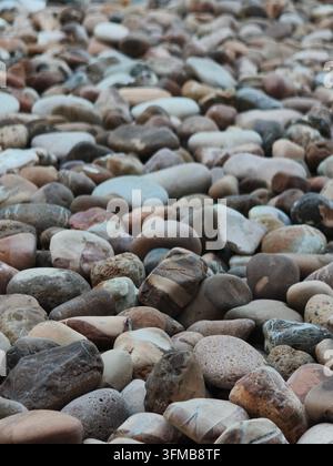 Un assortiment de pierres lisses et arrondies dans divers tons terreux, créant une texture naturelle Banque D'Images