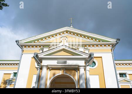 une vue architecturale sereine et détaillée d'une façade d'église avec des murs peints et des colonnes en pierre, capturée dans un cadre extérieur diurne à basse Banque D'Images