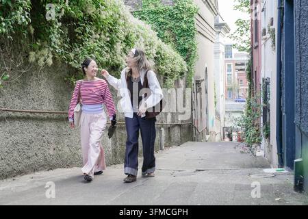 Diverses amies femmes marchant en montée en profitant de l'environnement urbain Banque D'Images