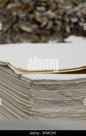 Pile de papier recyclé avec des matières premières en arrière-plan Banque D'Images