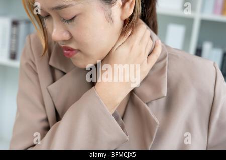 syndromes de bureau, femme massant des douleurs cervicales dues au travail et à l'aide d'un ordinateur, composite numérique d'une colonne vertébrale focalisée de douleurs cervicales et d'épaule symp Banque D'Images