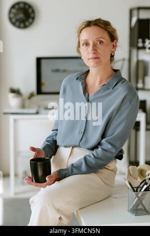 Portrait d'une femme d'affaires d'âge moyen tenant une tasse au bureau Banque D'Images