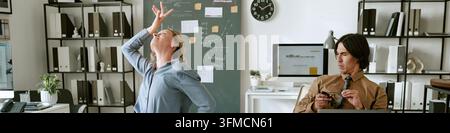 Femme heureuse dansant au bureau tandis qu'un collègue masculin regarde Banque D'Images