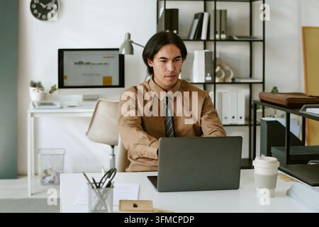 Homme d'affaires concentré travaillant sur un ordinateur portable au bureau Banque D'Images