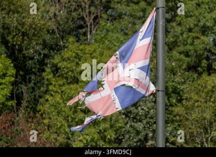 Drapeau Union Jack déchiré et en lambeaux flottant encore dans la brise, attaché à un lampadaire, Worcestershire, Angleterre. Banque D'Images