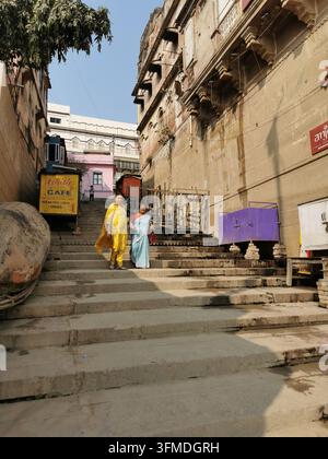 VARANASI, INDE - 23 JANVIER 2026 : Femmes descendant un escalier de pierre vers les ghats dans la vieille ville de Varanasi Banque D'Images