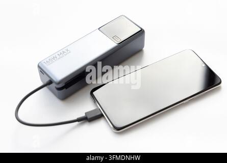Un chargeur portable alimente un téléphone mobile moderne via un câble Banque D'Images