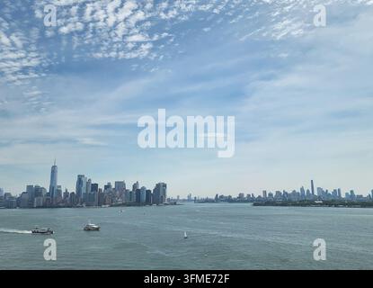 Vue panoramique lointaine de la skyline de Manhattan à travers la baie supérieure de New York avec des embarcations. Banque D'Images