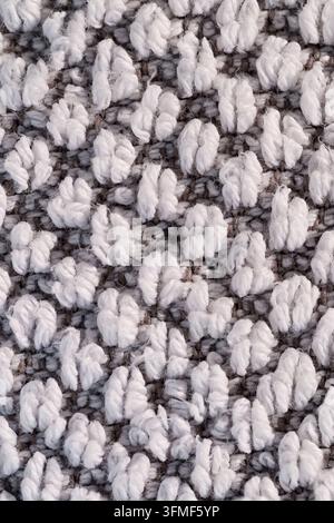 Grossissement d'un fil de boucle blanc sur une surface textile tissée grise, montrant une texture de fibre douce, un motif dense et un fond abstrait neutre. Banque D'Images